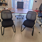 Sedia ospiti a slitta modello SeDo con schienale in rete e seduta imbottia e rivestita in tessuto nero ignifugo